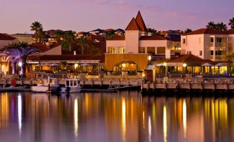 a marina at dusk , with boats docked in the water and buildings lining the shore at The Marina Hotel - Mindarie