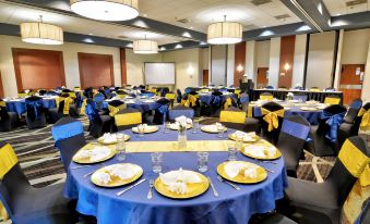 a large banquet hall filled with round tables and chairs , ready for a formal event at Holiday Inn ST. Petersburg N- Clearwater