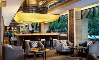 a modern hotel lobby with a bar and seating area , as well as a waiter behind the counter at Royal Ambarrukmo Yogyakarta