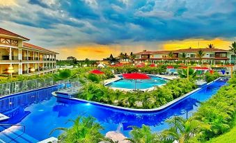 a resort with a large pool surrounded by lush greenery , including palm trees , and a restaurant nearby at Hotel Campestre las Camelias