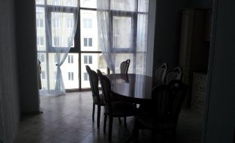 a dining room with a table and chairs , surrounded by large windows and white curtains at Luxury Apartment