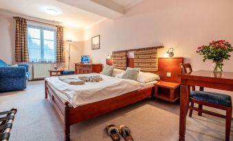 a large bedroom with a bed , desk , and chair , as well as a pair of slippers on the floor at Hotel Golfer