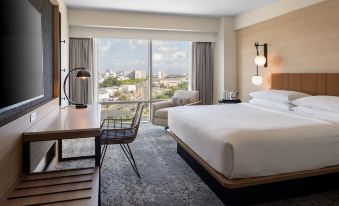 a hotel room with a large bed , a desk , a chair , and a window overlooking the city at Sheraton Puerto Rico Resort & Casino