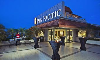 At night, a brightly decorated building houses a restaurant with outdoor seating where people are dining at Pan Pacific Hanoi