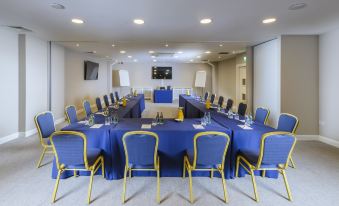 a conference room set up for a meeting , with chairs arranged in a semicircle and a tv mounted on the wall at The Ellison