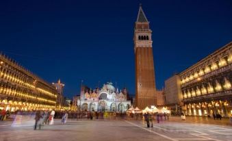 a nighttime view of the piazza san marco in venice , italy , with people walking around and a large clock tower visible in the background at Hotel President