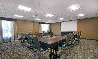 a conference room with a large table , chairs , and a projector screen , set up for a meeting or presentation at Homewood Suites by Hilton Chicago-Lincolnshire