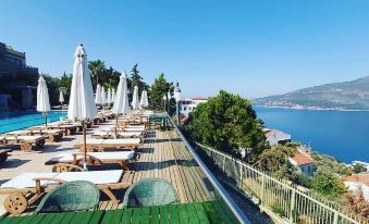 a rooftop deck overlooking a body of water , with several lounge chairs and umbrellas placed around the area at Happy Hotel Kalkan