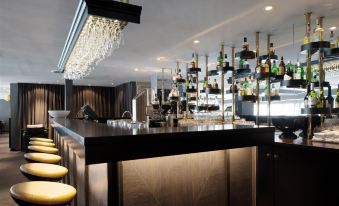 a well - lit bar with a large counter and numerous bottles of liquor on the wall at Scandic Ishavshotel