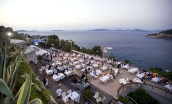 a large outdoor dining area overlooking a body of water , with numerous tables and chairs set up for a party or gathering at Duja Bodrum