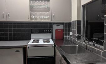 a modern kitchen with black and white tile backsplash , stainless steel appliances , and a red trash can at Prince of Wales Hotel