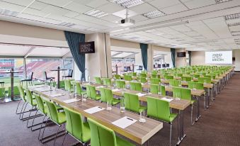 "a conference room with green chairs and tables , glasses , and water bottles , under a sign that says "" green "" on the ceiling" at Lindner Hotel Leverkusen Bayarena