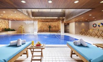 The hotel features a spacious indoor swimming pool with multiple loungers and an inflatable jacuzzi at Novotel Beijing Peace