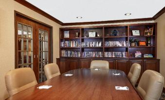 a wooden conference table surrounded by chairs in a room with bookshelves filled with books at Staybridge Suites Milwaukee Airport South