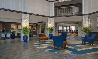 a large , modern hotel lobby with a seating area and a staircase leading to the second floor at Homewood Suites by Hilton Chicago-Lincolnshire