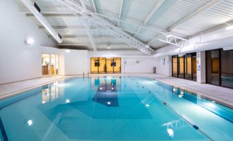 an empty indoor swimming pool with clear water , surrounded by white walls and a white ceiling at Holiday Inn Gloucester - Cheltenham