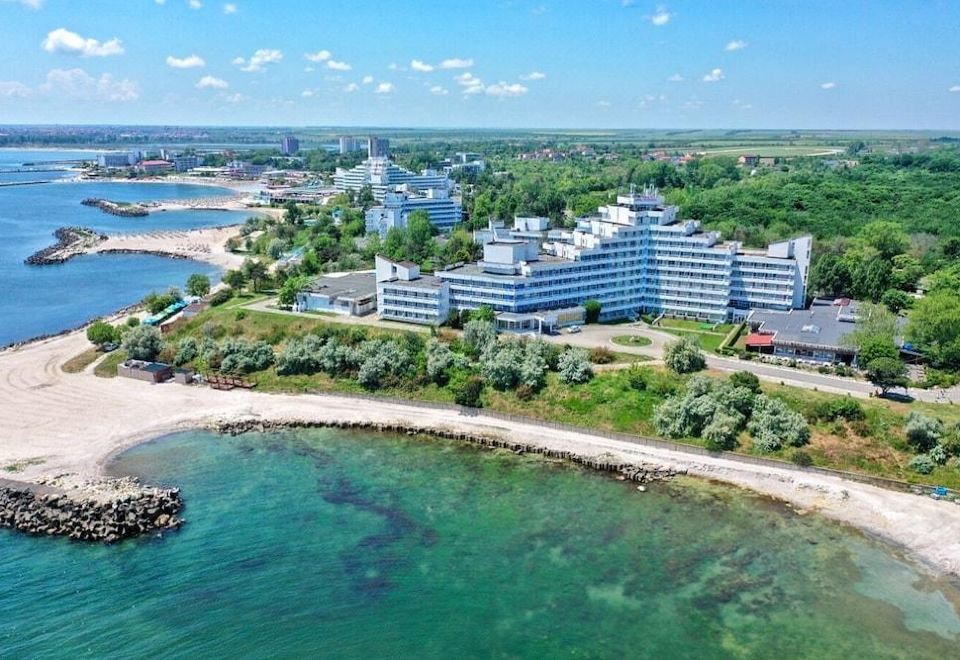 aerial view of a large white hotel surrounded by a sandy beach , with the ocean visible in the background at Hotel Opal