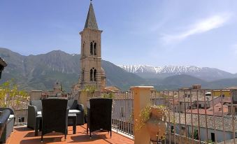 a rooftop patio with a view of a church and mountains , surrounded by chairs and tables at Legacy