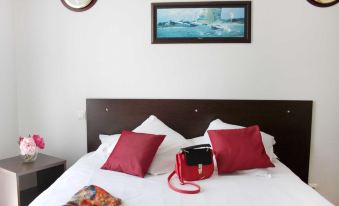 a bed with red pillows and a white comforter , along with a painting on the wall above it at Comfort Suites Pau Idron