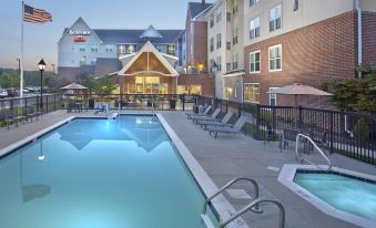 a hotel with a large swimming pool surrounded by chairs and umbrellas , as well as a patio area at Residence Inn Waldorf