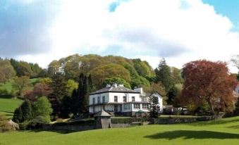 a large white house surrounded by trees and grass , located in a rural area at Ees Wyke Country House
