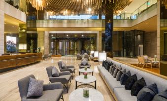 a large , modern hotel lobby with multiple couches and chairs arranged around a coffee table at Arize Hotel Sri Racha
