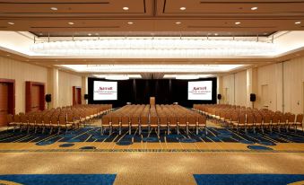 a large conference room with rows of chairs and a stage at the front , ready for an event at Montreal Airport Marriott in-Terminal Hotel