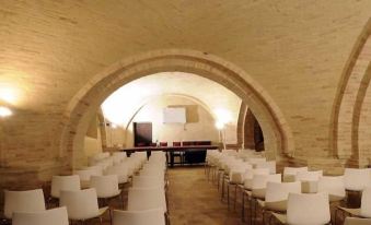 an empty , dimly lit room with white chairs arranged in rows under a large arched ceiling at Castello di Semivicoli