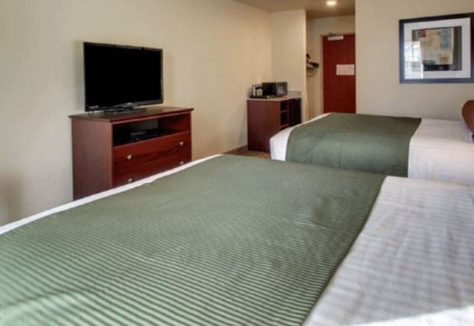 a hotel room with two beds , a tv , and a desk , all neatly arranged in a room with white walls at Cobblestone Hotel & Suites - Erie