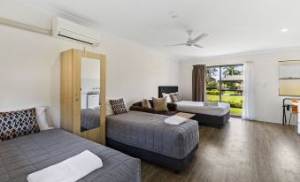 a modern , minimalist bedroom with three beds and a balcony view of a golf course at Lemon Tree Passage Motel