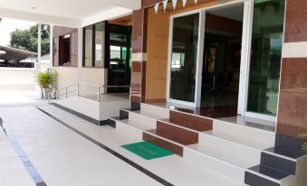 a modern building with large glass doors and a wooden staircase leading up to the entrance at Phetlada Pavilion & Resort
