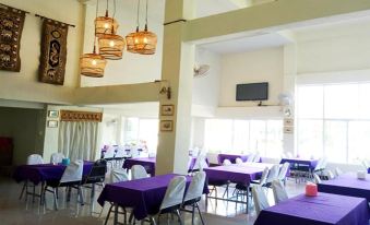 a large dining room with purple tablecloths and chairs , creating a vibrant atmosphere in the space at Amonruk  Hotel 2
