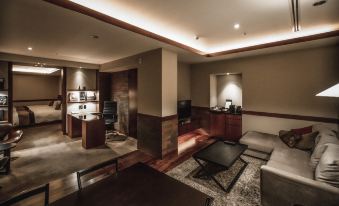 a modern living room with wooden floors , a brown couch , and a desk in the corner at Oarks Canal Park Hotel Toyama