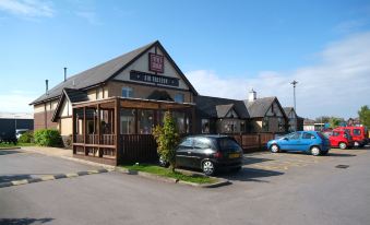 a small town with a building that resembles a cracker barrel restaurant , surrounded by cars parked in the lot at Premier Inn Blackpool Airport