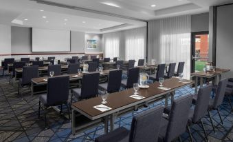 a conference room with rows of chairs and tables , a projector screen , and large windows at Courtyard Los Angeles Burbank Airport