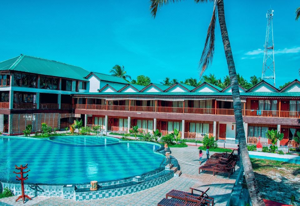 a large swimming pool is surrounded by lounge chairs and a building with red roofs at Holiday Inn Beach Resort