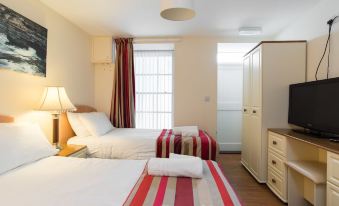a clean and well - organized hotel room with two beds , white walls , wooden furniture , and red and white striped bedspreads at Marine Apartment