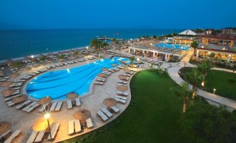 a large resort with multiple swimming pools , sun loungers , and palm trees near the ocean at Armonia Holiday Village & Spa