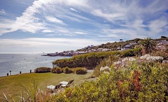 a picturesque coastal town with houses perched on a hillside , surrounded by lush greenery and blue skies at The Bay Hotel