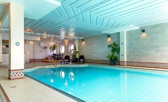 an indoor swimming pool with blue water , surrounded by white walls and a ceiling made of wood at Rodd Grand Yarmouth