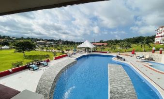 a large outdoor swimming pool surrounded by a patio area , with lounge chairs and umbrellas placed around the pool at Royal Elmount Hotel