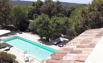 a large swimming pool is surrounded by trees and a house with a red tile roof at L'Atelier