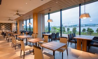 a modern restaurant with wooden tables and chairs , large windows , and a view of the water at Hotel Ichibata