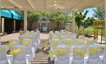 a wedding ceremony taking place under a covered area , with rows of white chairs arranged for guests at DoubleTree by Hilton Hotel Grand Junction
