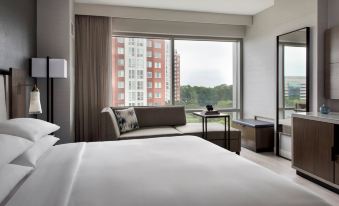a hotel room with a king - sized bed , a couch , and a view of the city outside the window at Bethesda North Marriott Hotel & Conference Center
