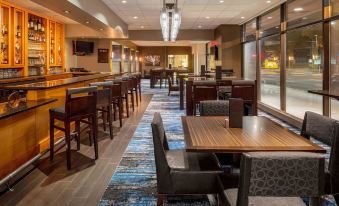 a modern restaurant with wooden tables and chairs , a bar area , and a carpeted floor at DoubleTree Suites by Hilton Minneapolis