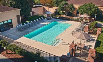 an outdoor swimming pool surrounded by chairs and umbrellas , providing a relaxing atmosphere for guests at Sonesta Select Raleigh Durham Airport Morrisville