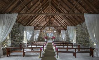 a traditional stone church with wooden benches and pews , decorated with white flowers and tissue paper , under a thatched roof at Mandarin Oriental, Canouan