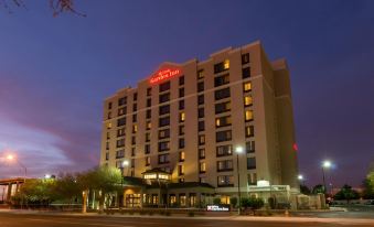 a large hotel building with many windows and a red sign on top , illuminated at night at Hilton Garden Inn Phoenix Airport North