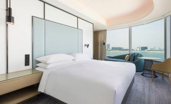 The modern bedroom features large windows, a white bed, and a wood-paneled accent wall at Four Points by Sheraton Hong Kong Tung Chung